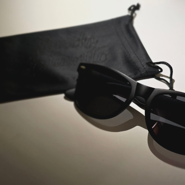 Matte black classic square frames and a black microfiber cloth, on a neutral backdrop by Kimchi Burrito Sunglasses.