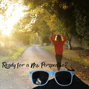 Lifestyle image showing a person from behind, seemingly contempating a sun-drenched, tree-lines path, with a pair of light blue sunglasses positioned prominently in the lower foreground. The overlay text ready "Ready for a New Perspective?"